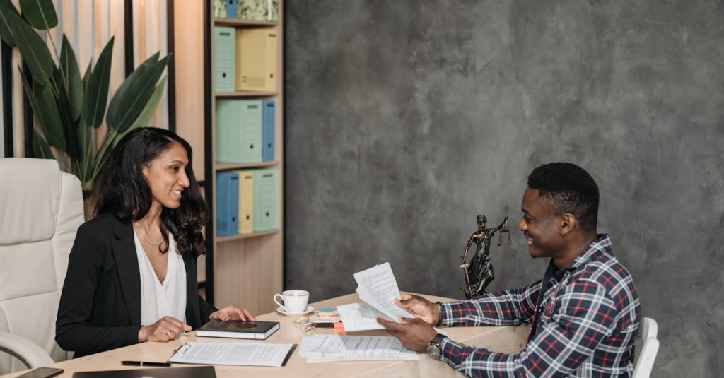 Two professionals having a discussion in a stylish office with paperwork and a laptop.