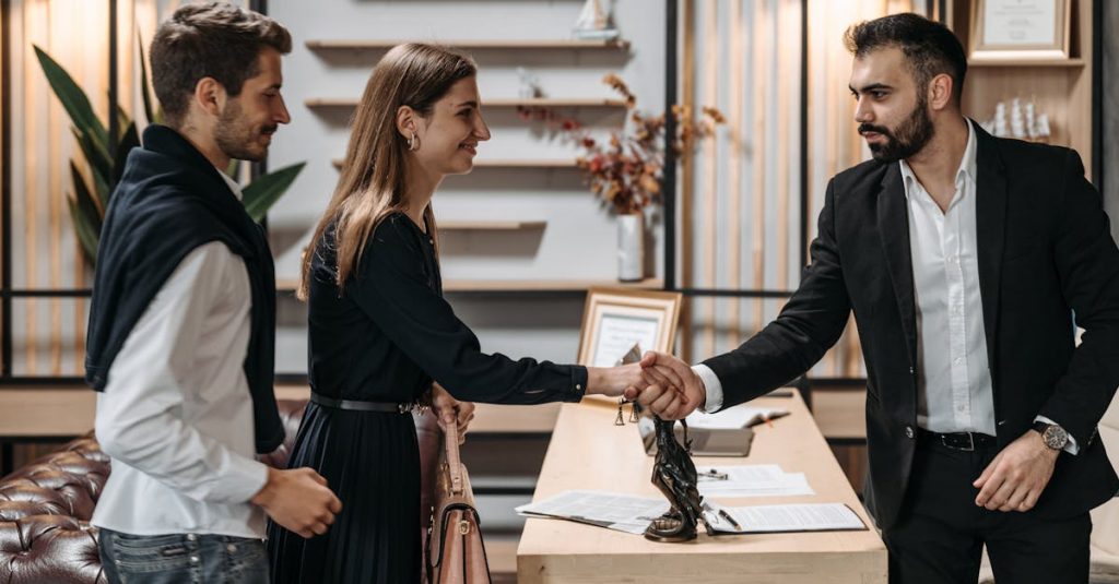 A professional meeting in a modern office with a couple shaking hands with a businessman.